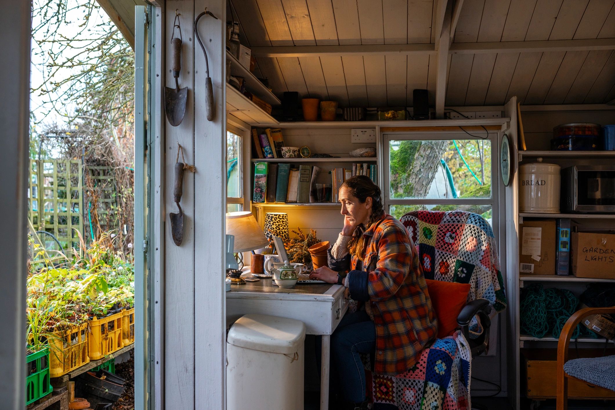 Woman working on a laptop in a cozy garden writing space
