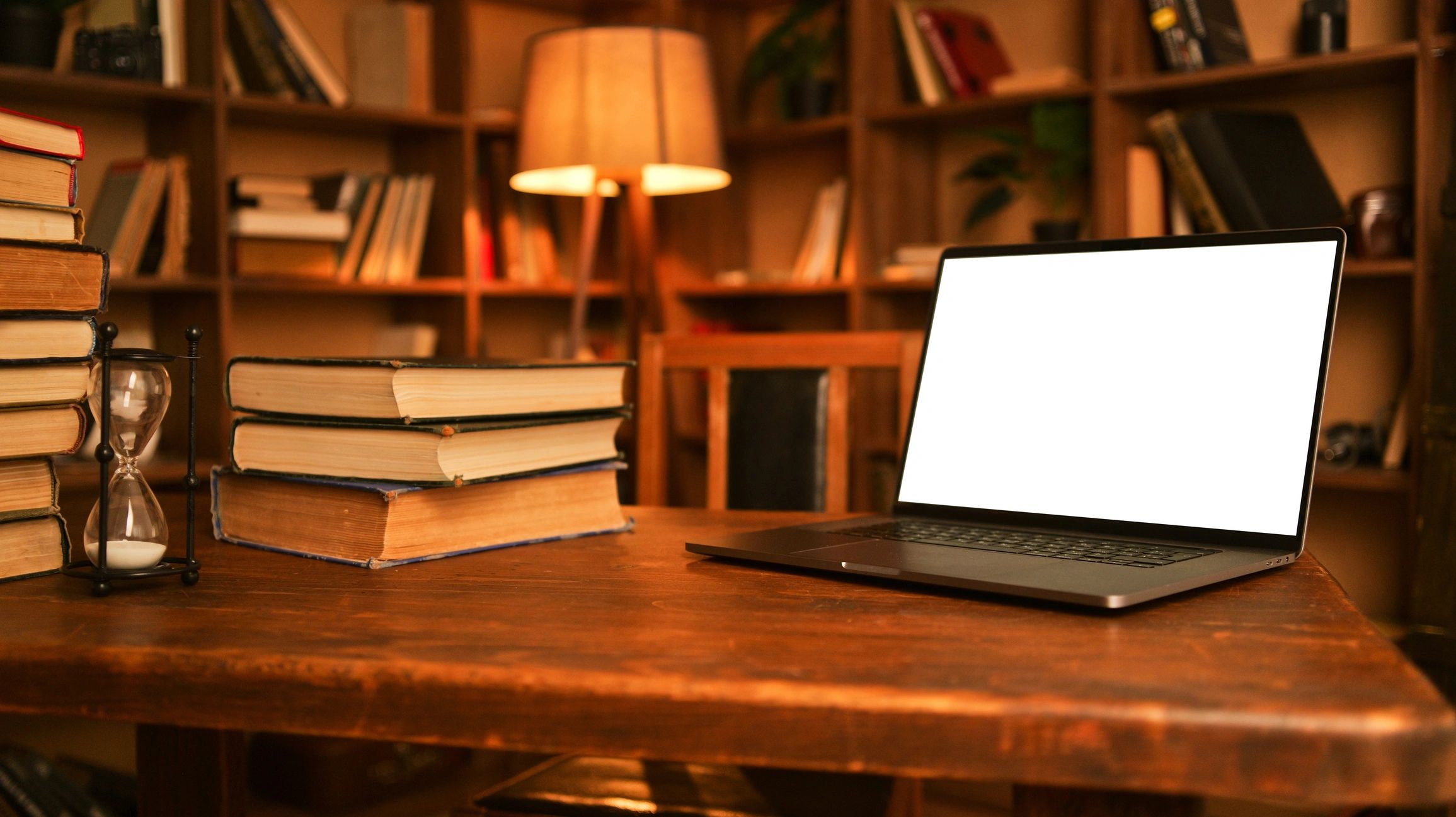 Warm writing desk with books and laptop in a cozy library setting