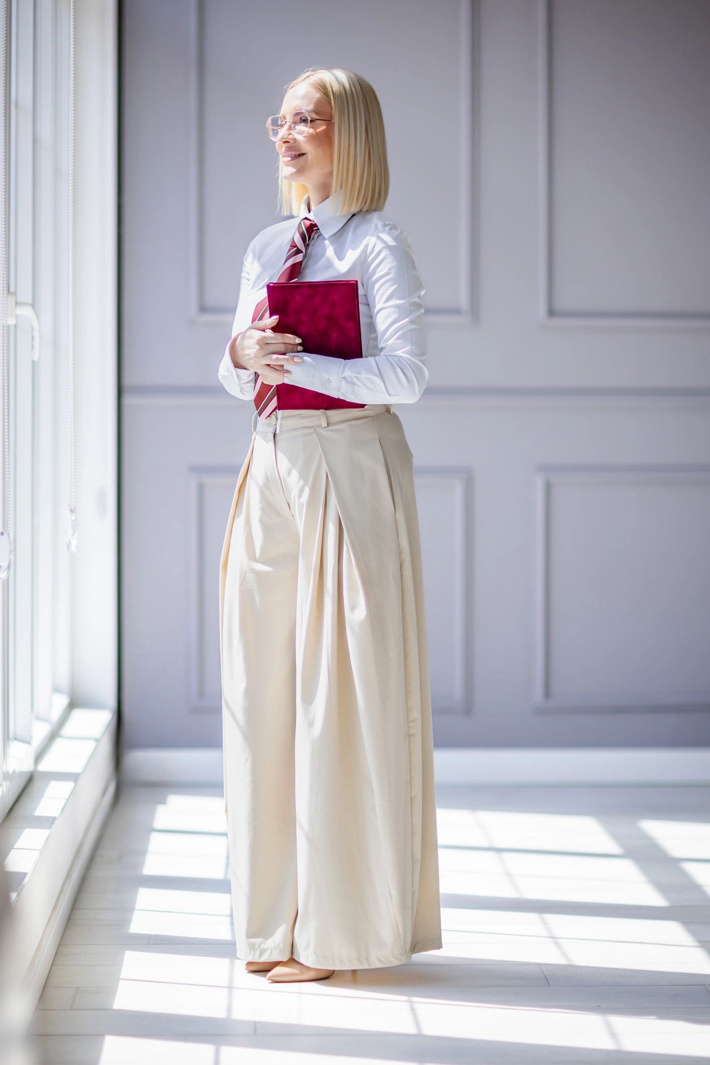 Portrait of a professional woman holding a notebook near a bright window