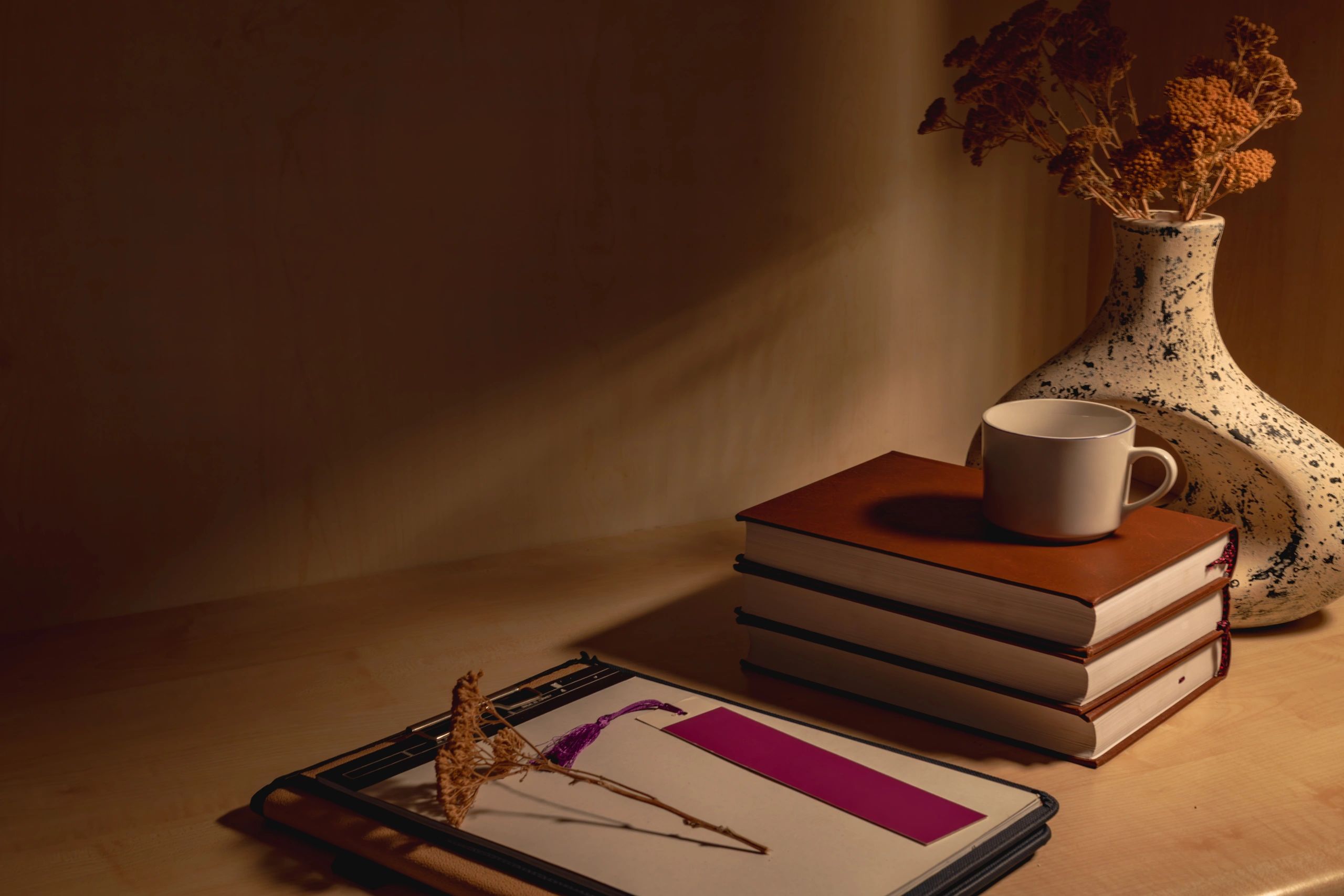 Styled writing desk with books, notebook, coffee, and dried flowers